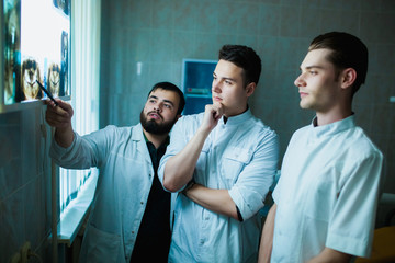 Dental clinic. A group of professional doctors discusses dentistry treatment on x-rays in the...
