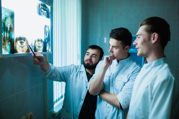 Dental clinic. A group of professional doctors discusses dentistry treatment on x-rays in the...