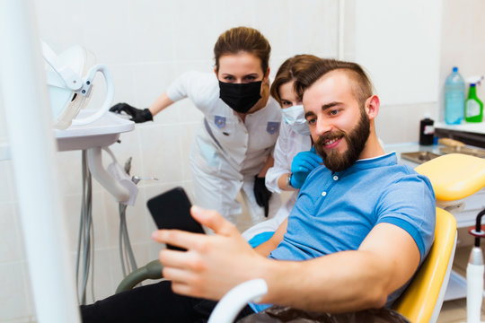 Dental clinic. A satisfied patient takes a selfie picture with the doctors to leave a review on the hospital website.