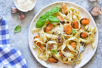 Tagliatella pasta with mussels and cream sauce on the kitchen table. View from above.