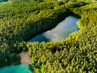 Aerial view of beautiful green waters of lake Gela. Birds eye view of scenic emerald lake surrounded by pine forests.