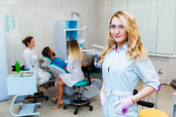 Fototapeta premium Dental clinic. Portrait of a professional dentist on the background of a working team of doctors. Concept of medical education and medical insurance