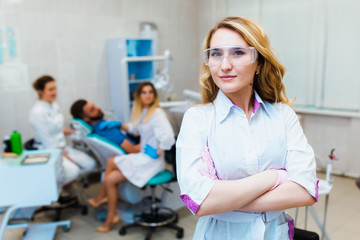 Obraz premium Dental clinic. Portrait of a professional dentist on the background of a working team of doctors. Concept of medical education and medical insurance