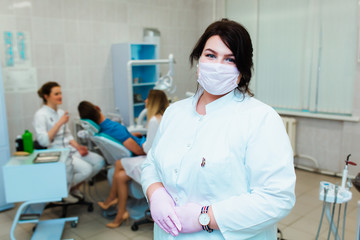 Fototapeta na wymiar Dental clinic. Portrait of a professional dentist on the background of a working team of doctors. Concept of medical education and medical insurance