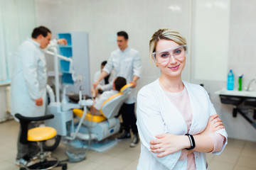 Fototapeta premium Dental clinic. Portrait of a professional dentist on the background of a working team of doctors. Concept of medical education and medical insurance