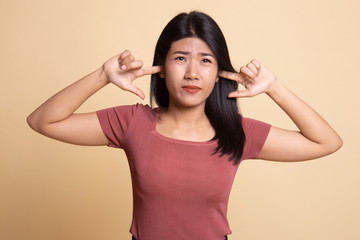 Young Asian woman block both ears with fingers.