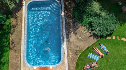 Happy family relaxing by swimming pool, aerial drone view from above of parents and kids have fun on vacation, family weekend on resort