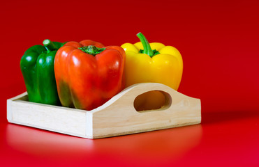 Summer of sweet bell pepper in wood box on red background.