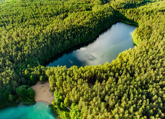 Aerial view of beautiful green waters of lake Gela. Birds eye view of scenic emerald lake surrounded by pine forests.