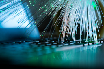 Glowing colorful optical fibres over laptop computer keyboard , image for background.