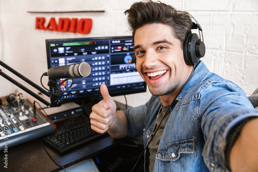 Wall mural Handsome happy young male radio host broadcasting