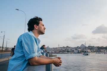 A young man on the bridge looks into the distance on the city.