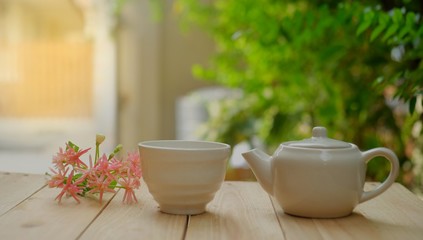a glass of hot tea and tea pot with lemon on a old wooden table.  garden background.