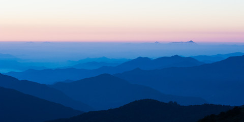 Obraz premium Poonhill view of mountains around Annapurnas. Warm pink and orange sunrise light over Annapurna mountain range with blue sky and beautiful clouds, Morning on Poon hill in Himalayas, Nepal.