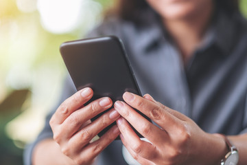 Closeup image of a woman holding  and using mobile phone
