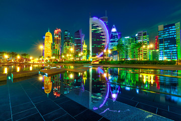 The colorful towers of Doha West Bay reflection by night. Evening skyline over the Persian Gulf, Middle East, Doha, Qatar. Night urban scene.