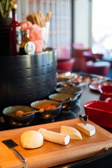 From above tasty cheese pieces of different forms and knives on wooden cutting board