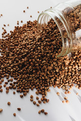 Raw buckwheat in glass on white background