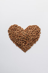 Raw buckwheat on white background shaped as heart symbol