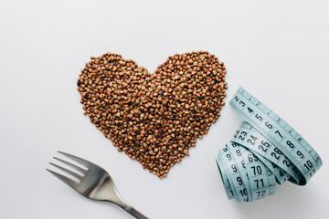 Raw buckwheat on white background shaped as heart symbol