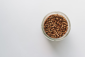 Raw buckwheat in glass on white background