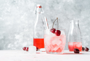 Cherry lemonade in bottles and glasses garnished with sweet cherries