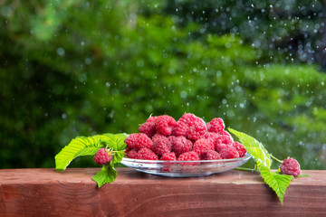 Raspberry berries on a wooden table. Summer mood. A treat. Dark background.