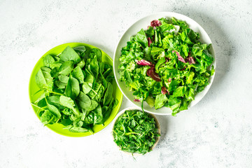 Tree bowls with mixed shredded salad leaves on white background, top view