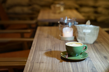 Hot Art Latte in the green cup on the wood table