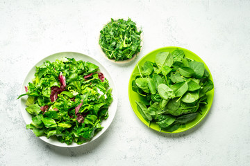 Tree bowls with mixed shredded salad leaves on white background, top view