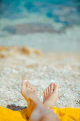 woman legs on yellow blanket at sunny beach close up