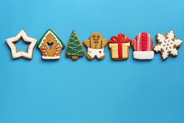 A variety of Christmas gingerbread in a row on a blue background. Top view, flat lay, copy space. The concept of the holiday.