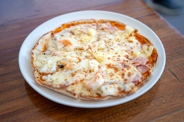 Simple and basic normal Isolated full circle Pizza in White dish on wood table.