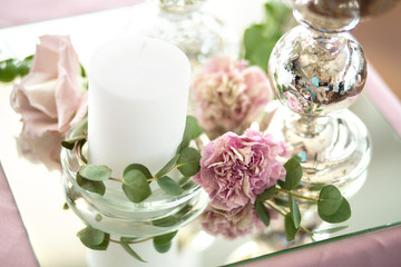 The wedding table setting for the newlyweds is decorated with fresh flowers of carnation, rose, anthurium and eucalyptus leaves. Silver candlesticks, white candles. Wedding floristry. Close-up details