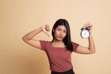 Young Asian woman thumbs down with a clock.