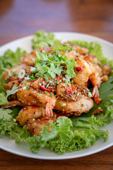 Fried Seafood shrimp prawn fish mussel squid fish on the salad vegetagle in white circle dish on wood table.