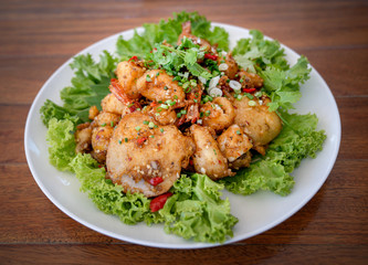 Fried Seafood shrimp prawn fish mussel squid fish on the salad vegetagle in white circle dish on wood table.