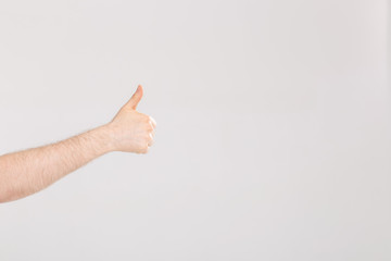 Closeup of male hand showing thumbs up sign against white background with copy space