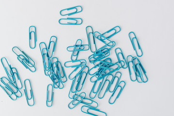 Pile of blue paper clips on blue background