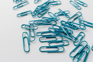 Pile of blue paper clips on blue background
