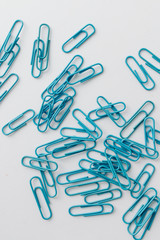 Pile of blue paper clips on blue background