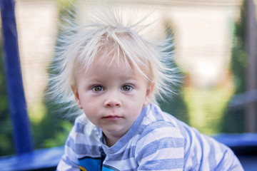 Cute little boy with static electricy hair, having his funny portrait taken outdoors