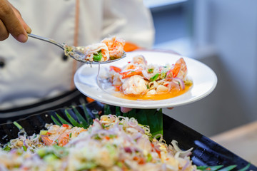 Traditional Thai spicy Noodle vermicelli with seafood shrimp squid and Thai herb on cook hand. © Surachetsh