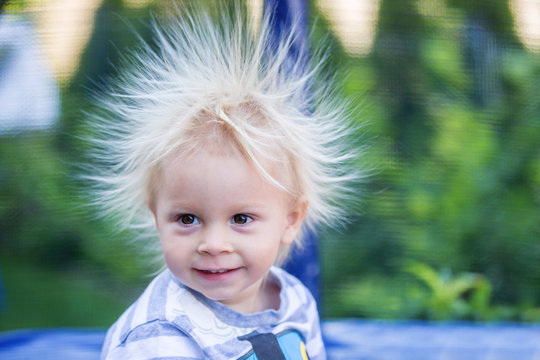 Cute little boy with static electricy hair, having his funny portrait taken outdoors