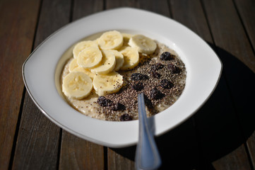 Bowl of porridge with banana, fruit and seeds