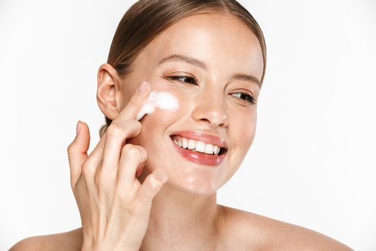 Image of attractive half-naked woman smiling while washing her face with foaming facial cleanser