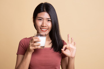 Healthy Asian woman drinking a glass of milk show OK sign.