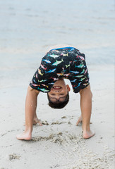 Little Boy with glasses at the beach upside down being silly