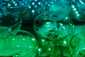 empty champagne glasses on the table with LED illumination.  bar table after the party with transparent glass glasses and the remnants of champagne. concept of a fun party, celebration, wedding, prom
