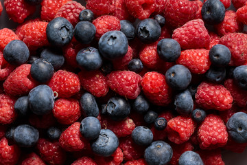 close up view of fresh ripe mixed raspberries and blueberries